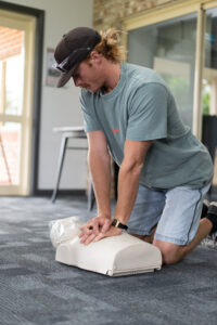 a man practices giving cpr to a manakin during a first aid class