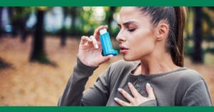 A woman using an inhaler, holding her chest with a look of distress, possibly having an asthma attack