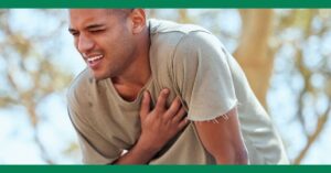 A man in a green t-shirt holding his chest in pain, possibly experiencing a heart attack.